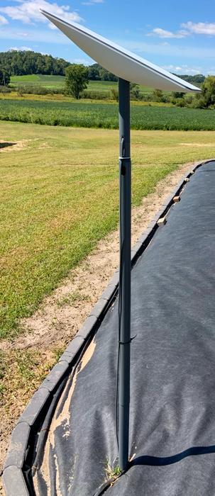 A Starlink dish on a tall pole mount with the cable routed neatly down the mast